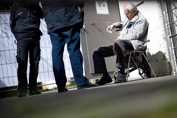 Defendant Oskar Gr&ouml;ning sits near a courtroom entrance during a trial break in L&uuml;neburg, Germany, April 2015. Julian Stratenschulte picture-alliance/dpa/AP Images