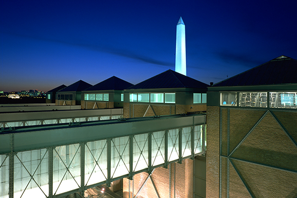 A nighttime view of the US Holocaust Memorial Museum with the Washington Monument in the background.&nbsp;Timothy Hursley for the Museum