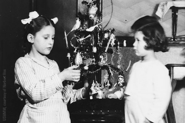 Norbert Obstfeld (right) poses next to a Christmas tree with Raymonda Verhage, the daughter of his rescuers, in December 1943. USHMM, courtesy of Norbert Vos