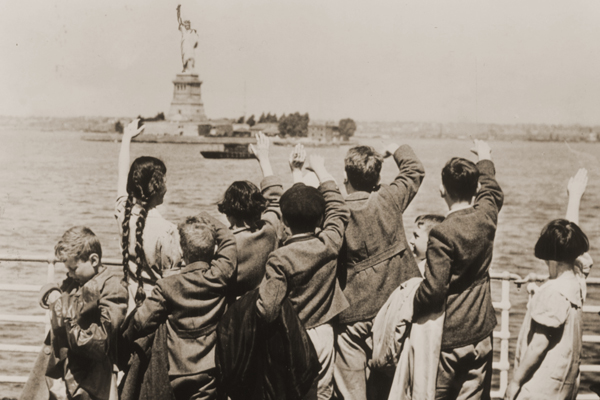 Jewish refugee children wave at the Statue of Liberty as the SS President Harding steams into New York harbor, 1939. They are among a group of 50 Jewish child refugees from Vienna who came to the United States as part of a rescue effort organized by Americans Gilbert and Eleanor Kraus. US Holocaust Memorial Museum, courtesy of Anita Willens